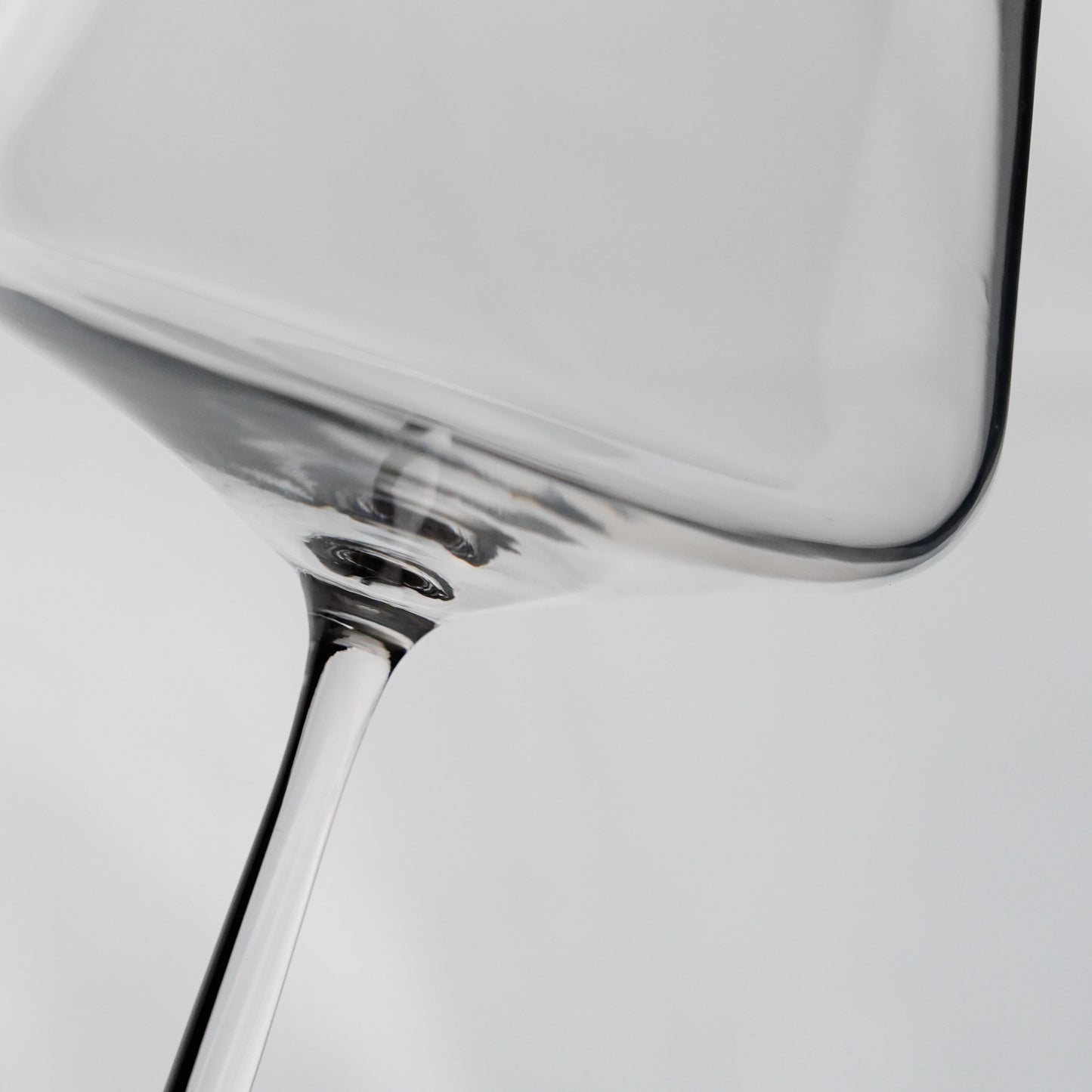 Close-up of a clear glass wine glass on a plain background.