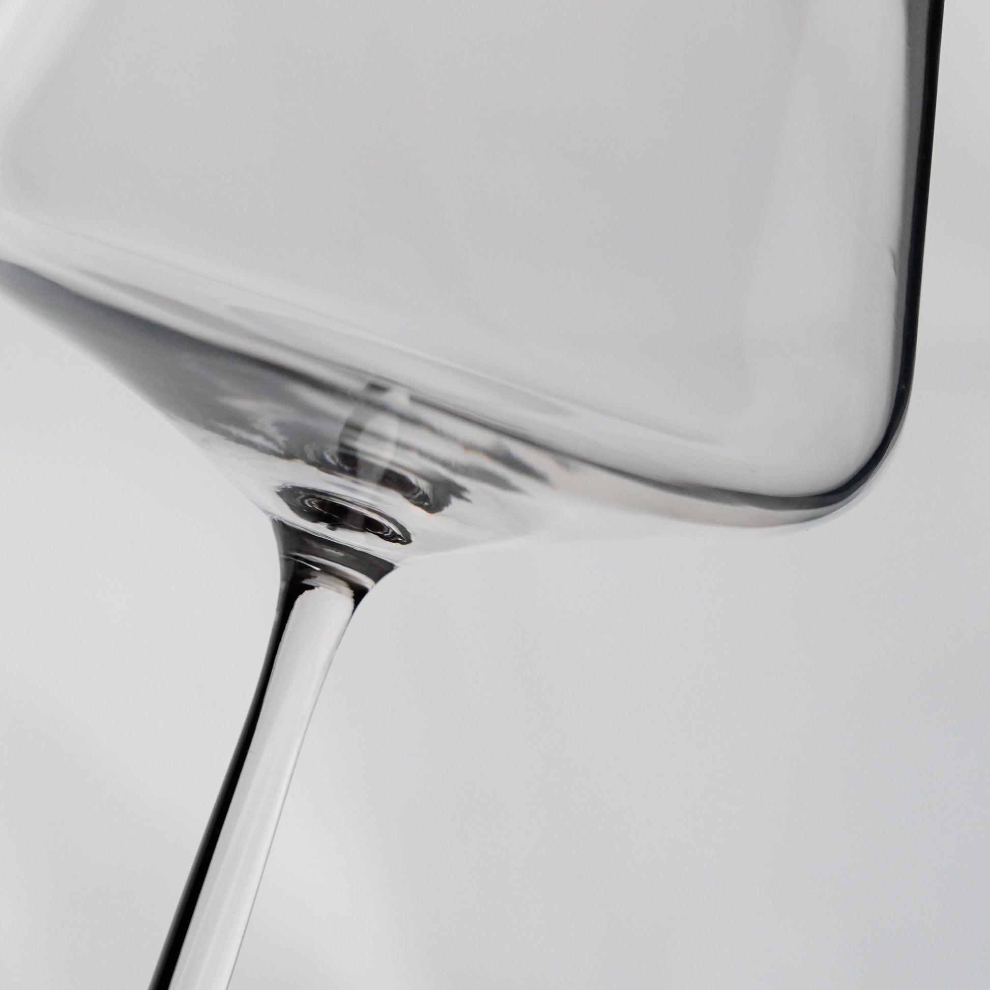 Close-up of a clear glass wine glass on a plain background.